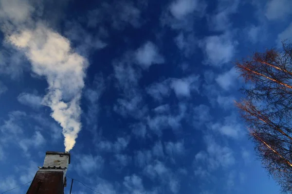 ふわふわの雲と空に白い煙を放出する家の上に古い煙突 — ストック写真