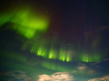 Gece bulutlu yeşil ve kırmızı aurora.