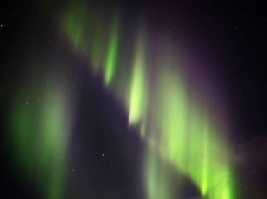 Gece gökyüzünde yeşil aurora borealis perdeleri.