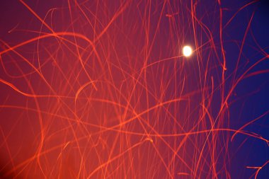 Gökyüzünün önünde parlak ay ve yıldızlarla dağılmış kıvılcımlar..