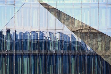 Modern glass facade in Berlin with reflections of skyline and pavement.
