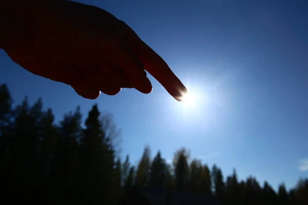 Pointing at the sun on a clear blue sky.