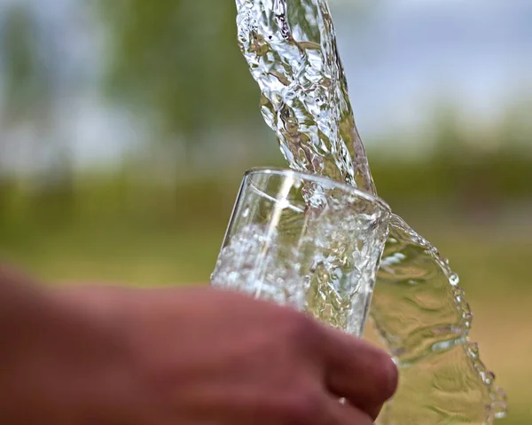 Water is poured in a glass and flows over.