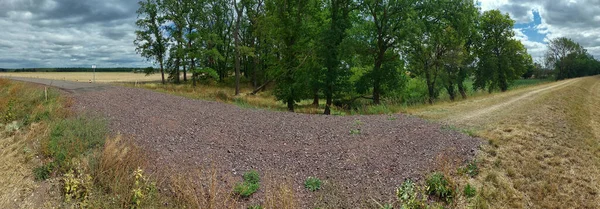 Panorama of small road ending in gravel and dirt road.