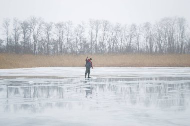 Novopskov, Ukrayna - 2 Ocak 2021: Kışın elinde matkapla gölette bir balıkçı balık tutacak. Kırsalda kış balıkçılığı.