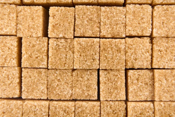 Refined sugar cubes on white background. Brown sugar cubes in background