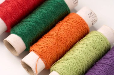 Dikiş iplikleri. Beyaz izole edilmiş arkaplanı olan bir iplik makarası. Çoklu renkli dikiş iplikleri arkaplanı.