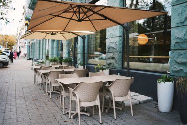 Kasabada boş kafeler var. Yazlık kafe terası. Bir kafede yemek masaları ve sandalyeler.