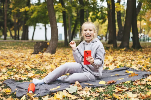 Gen z tiener meisje met behulp van smartphote buiten in de herfst tijd. Rechtenvrije Stockafbeeldingen