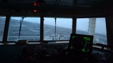Fırtınada bir gemi. Köprüden görüntü. Radar ve kontrol panelinin görüntüsü. İyi atıştı. Yüksek dalgalar gemiyi vurur. Suda beyaz köpük.