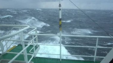 Fırtınada bir gemi. Köprüden görüntü. Gemi dalgalara tırmanıyor. Sıçramalar. Pencerede tuzlu su var. İyi atıştı. Yüksek dalgalar gemiyi vurur. Suda beyaz köpük.