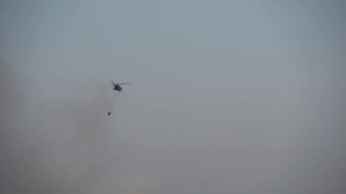 Helikopter kargoyla birlikte uçar. İpin altından bambi kovası.