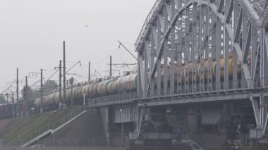 Tren tank taşıyor. Sarı tanklar. Yük treni. Benzin. Yağ. Sıvı. Tanklardan, arabalardan sonra. Tren köprüye girer.