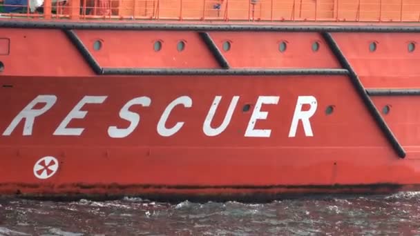 Vaso de rescate. Naranja. A bordo: Rescatador. Primer plano. El lado rojo del barco y el agua. — Vídeo de stock