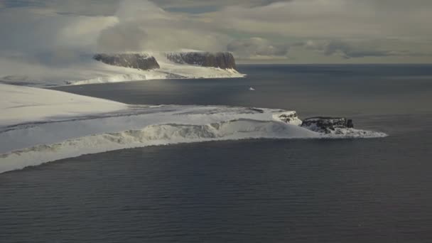 Skály ve sněhu na pobřeží. Horský mys ve sněhu. Kameny v mlze na břehu. Arktida. Letecký pohled. Arktická krajina. Severní pohled. — Stock video