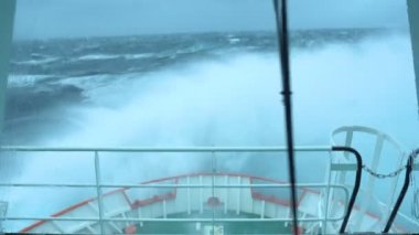 Fırtınada bir gemi. Bir sürü sıçrama. Köprüden görüntü. Gemi dalgalara tırmanıyor. İyi atıştı. Yüksek dalgalar gemiyi vurur. Suda beyaz köpük. Çok güçlü bir fırtına. Pruva dalgaları keser