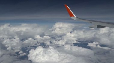 Uçak kanadı bulutun üzerinden uçuyor. Uçak penceresinden bak. Kanadın yanında kümülüs bulutu var. Bulutlara güzel bir manzara