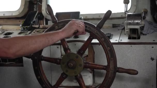 Wooden steering wheel is turned by hand. Steering wheel turns left and right. Old tug inside. Bridge of an old boat — Stock Video