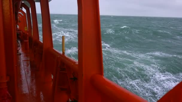 Bordschiff im Sturm. Rote Seite des Schiffes, grünes Meer. Hohe Wellen. Starkes Pitchen auf den Wellen Stock-Filmmaterial