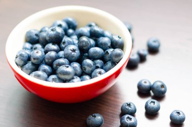 Ahşap masada kırmızı bir kasede yaban mersini..