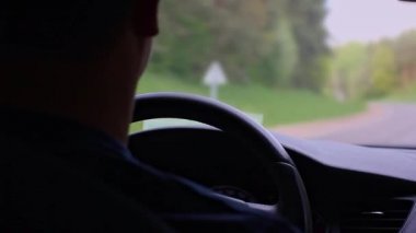 İnsan, ormanın güneşli manzarasında otoyol boyunca araba sürer..