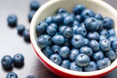 Ahşap masada kırmızı bir kasede yaban mersini..