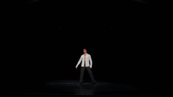 Young man in distance in unbuttoned white shirt,legs wide apart, dancers pose,turning head from right to left, running woman on heels behind,dark stage. Concept of intuition,sense of presence. — Stock Video