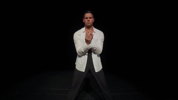 Young male ballroom dancer with bare breast,strong pectoral muscles,abs,in open white shirt,black trousers on dark backdrop,expressing passion.Solo dance and search for dance partner concept,midpoint. — Stock Video