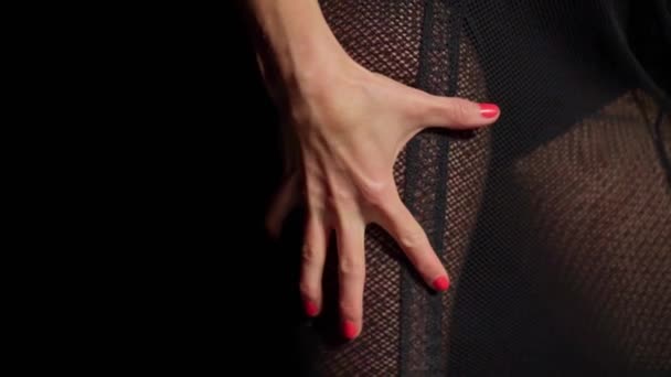 Zbliżenie damskiej dłoni z czerwonym manicure namiętnie rozciąga tkaninę krótkiej czarnej siateczki sukienki tanecznej.Nogi w rajstopach, czarny spód trykotu.Odzież erotyczna, maskarada, nieokreślona koncepcja tożsamości — Wideo stockowe