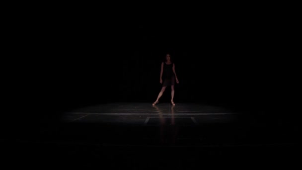 Női báli táncos jön ki a sötétből a színpadon, lassú rugalmas lépéseket latin-amerikai tangó tánc stílusban, teszi a kéz mozgását, mint a virág kinyílik, hajlító test.Fekete ruha, balett, hosszú távoli lövés. — Stock videók
