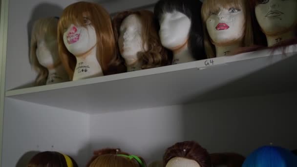 3 étagères de perruques dans différentes coiffures, coupes de cheveux teintes en différentes couleurs, mettre sur des têtes de mannequins, rack intégré dans le mur.Vieilles bases, visages avec maquillage.. — Video