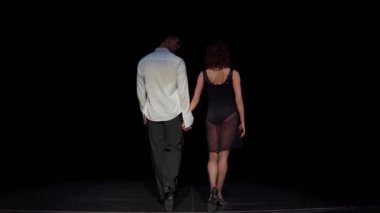 Kadın ve erkek balo dansçıları sahne karanlığına doğru yürür, yavaşça yürürler, el ele tutuşurlar ve birbirlerine bakarlar, siyah-beyaz dans kostümleri giyerler, arka manzara. Dans gösterisi konseptinin sonu..