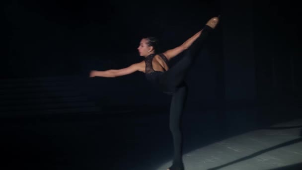 Fiatal gyönyörű nő, női műkorcsolyázó feszes öltönyben Biellmann pörgő korcsolyázást végez hátulról szemközti kézzel, bal kar kinyújtva előre, jégpályán sötétben.Lassú mozgás. — Stock videók
