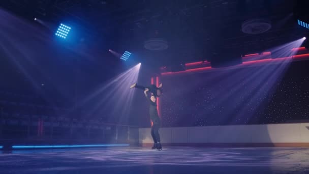 Figure skaters couple performs complex overhead lift,man holds woman parallel to ice on his outstretched arms, her legs in longitudinal split,then on one arm, rotating around. Rehearsal.Distant shot. — Stock Video