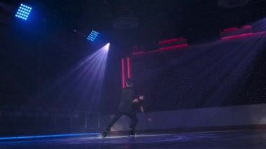 Artistik patinajcılar spot ışıklarında sabit rotasyonel kaldırma yaparlar. Erkek kadını iki ayak bileğinden tutarak kollarını kavuşturur, döner, kadın kolları düz bir şekilde buzun üzerinde süzülür. Prova