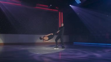 Artistik patinajcılar spot ışıklarında sabit rotasyonel kaldırma yaparlar. Erkek kadını iki ayak bileğinden tutarak kollarını kavuşturur, döner, kadın kolları düz bir şekilde buzun üzerinde süzülür. Prova