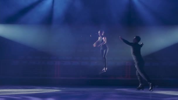 Lanzar y saltar técnica en par de patinaje artístico, cámara lenta.Los patinadores hacen elemento obligatorio, compañero masculino lanza a la mujer en el aire, ella hace varios giros, aterriza suavemente en el hielo.Volar girando en salto. — Vídeo de stock