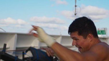 Çıplak gövdesiyle dışarıda egzersiz yapan genç ve güçlü bir adam.