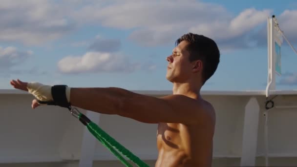 Jovem homem bonito alonga corpo com sistema de cinta de treinamento de banda de resistência — Vídeo de Stock