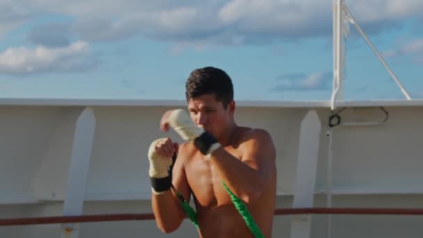 Красавчик занимается боксом и теневым боксом с системой ремешка сопротивления на открытом воздухе — стоковое видео