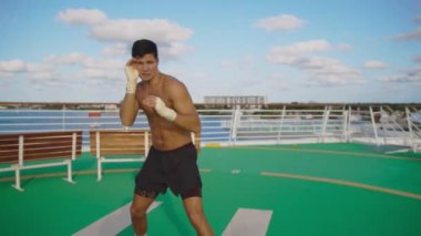 Yakışıklı, güçlü, güzel vücutlu, çıplak bir sporcu helikopter pistinde gölge boksu yapıyor.