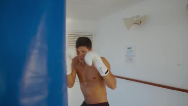 Guapo boxeador hombre cajas saco de boxeo al aire libre en ambiente industrial — Vídeos de Stock