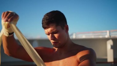 Beyaz tişörtlü yakışıklı adam boks antrenmanına başlamak için sargılarını sarar. 