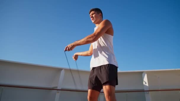 Athletic young man in white t-shirt jumps on rope outdoor — Vídeos de Stock
