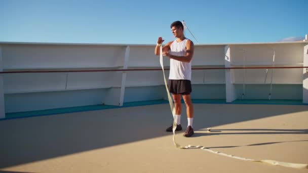 Atrakcyjny sportowiec w białej koszulce kołowrotki się strony owija, aby rozpocząć trening bokserski na świeżym powietrzu — Wideo stockowe