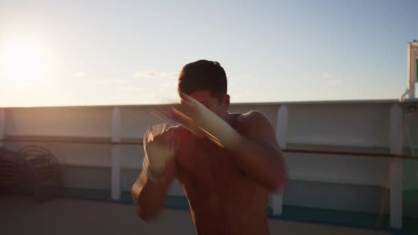 Красивий молодий чоловік з голим торсом здійснює тіньовий бокс на борту круїзного корабля — стокове відео