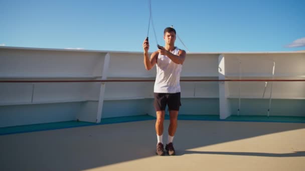 Handsome athletic young man in white t-shirt jumps on rope onboard cruise ship — Stock videók