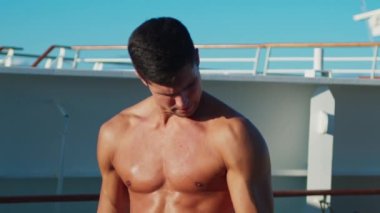 Yakışıklı genç adam bir yolcu gemisinde egzersiz yapıyor.