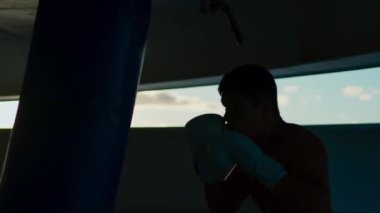 Attractive young man practices box punching bag outside onboard a cruise ship