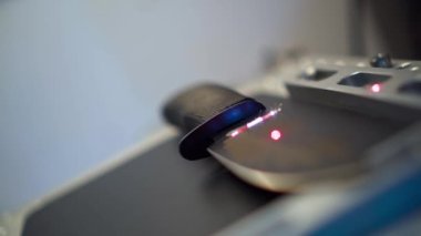 Laser engraving process zoom out diagonally,drawing feathers pattern on hunting knife surface, close-up, side view. Working with laser on metal,workshop concept. Ray movement from handle to blade tip